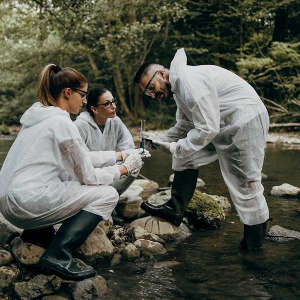 Team of three field researchers analyzing water samples from a river