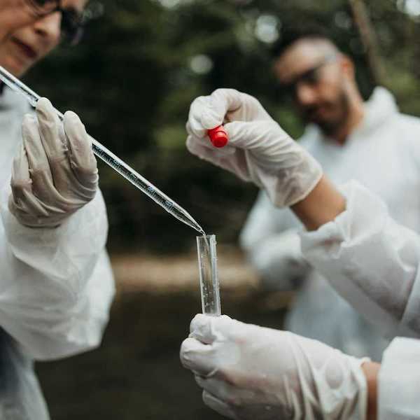 Team of three researchers in white protective coats taking water samples