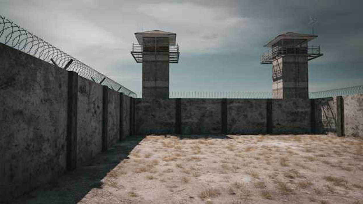 The exterior of a prison with prison towers and barbed wire