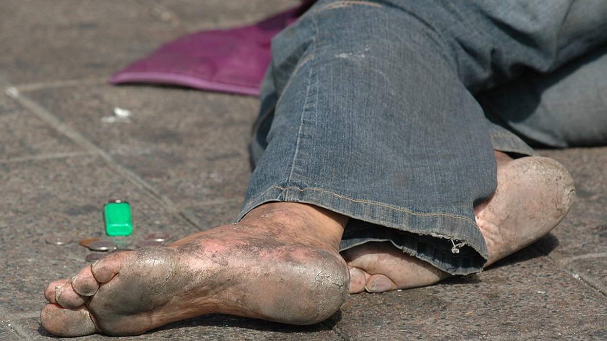 the feet of a homeless person lying on the ground