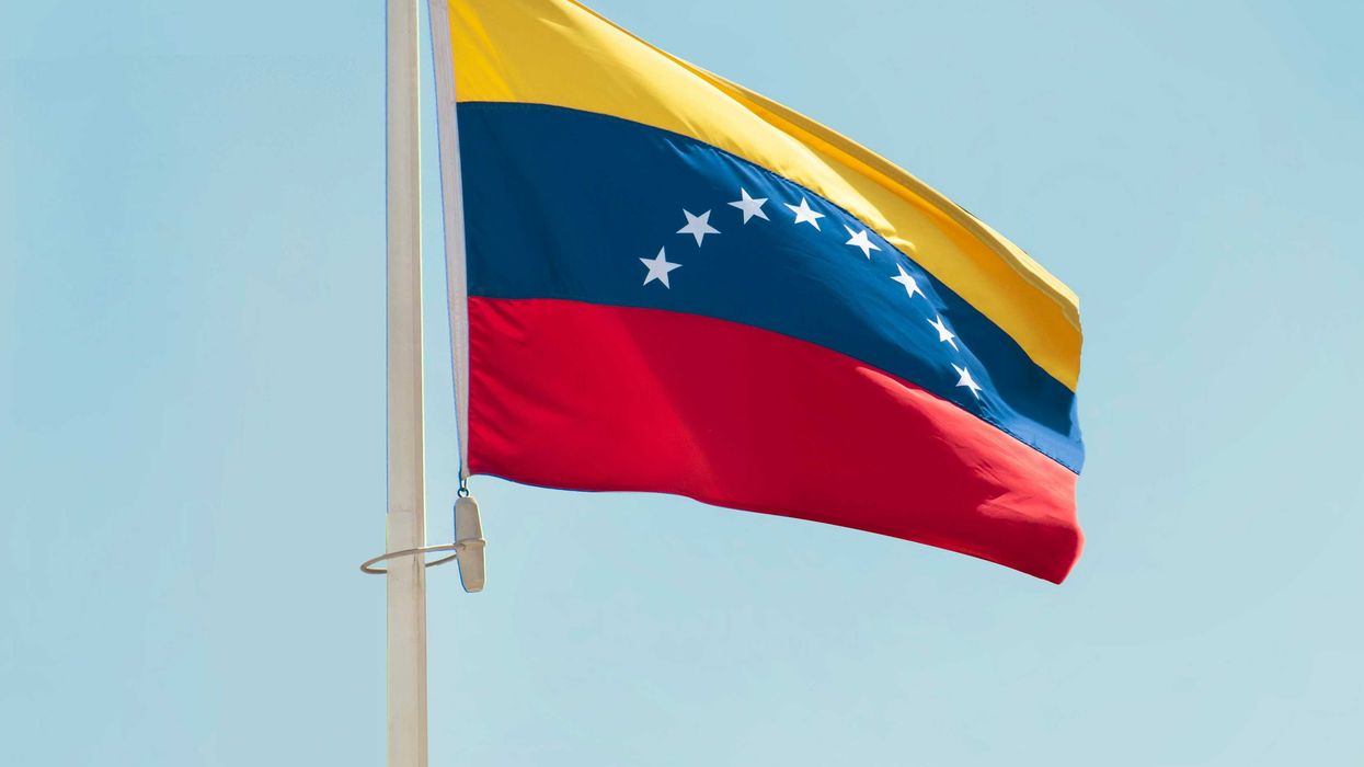 The flag of Venezuela with a blue sky in background.