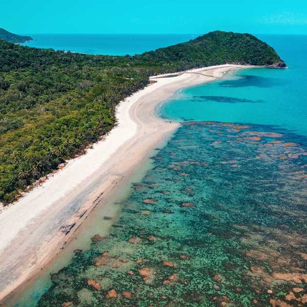 The Great Barrier Reef from above. Underwater, but visible, reef formation, with azure blue water and sky and land extendinginto ocean.