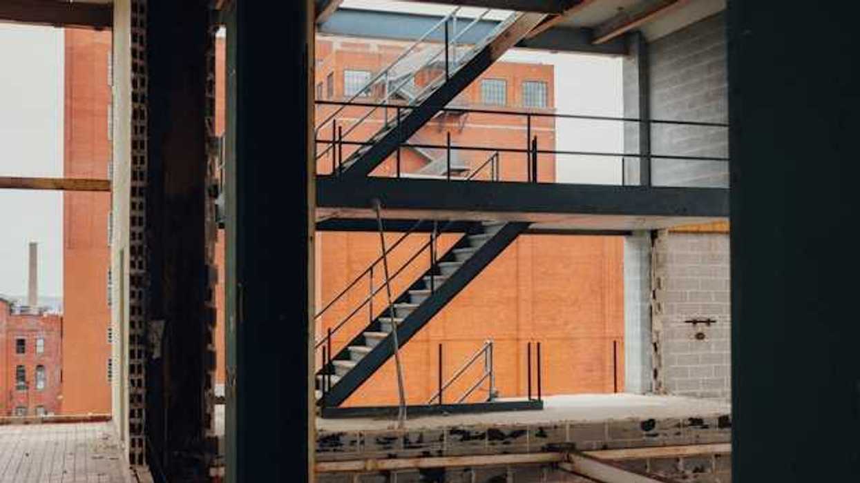 The interior of a building under construction with a brick building in the background