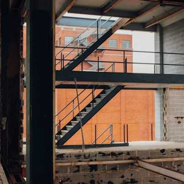 The interior of a building under construction with a brick building in the background