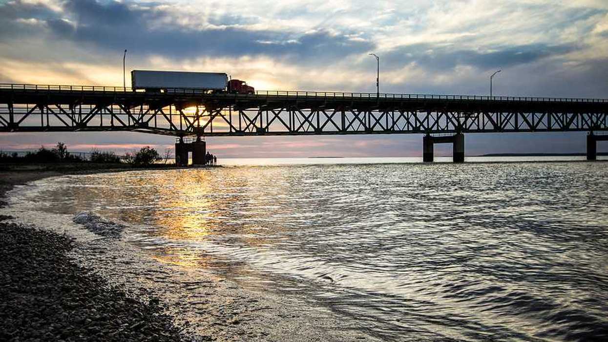 The Mackinaw Bridge stretching across a body of water at sunset