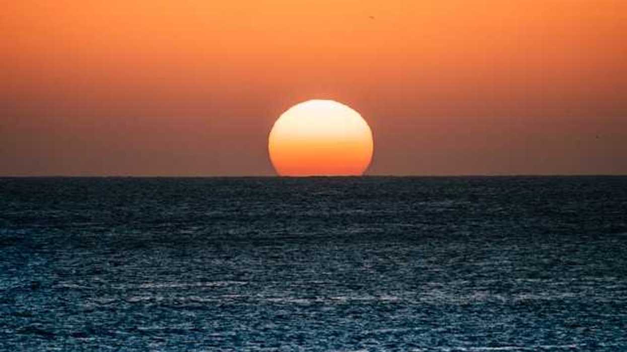 The ocean with the setting sun on the horizon