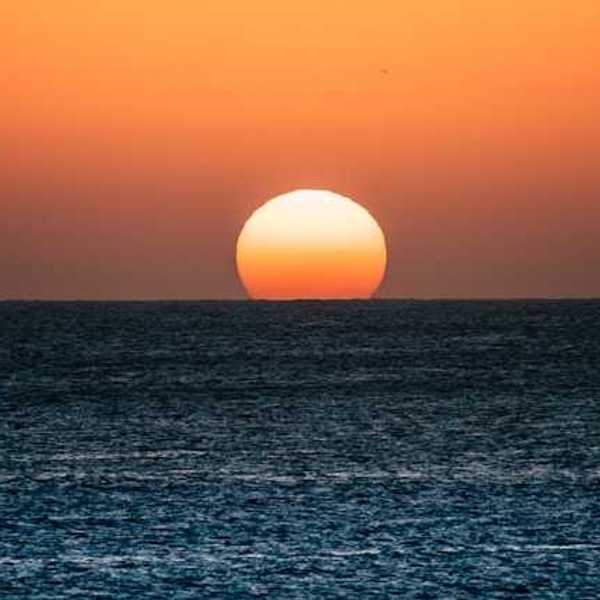 The ocean with the setting sun on the horizon