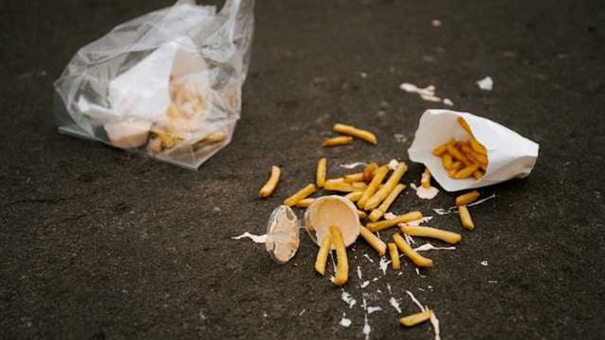 The remnants of a lunch on the sidewalk wrapped in plastic