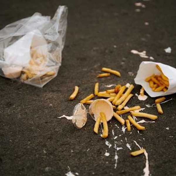 The remnants of a lunch on the sidewalk wrapped in plastic