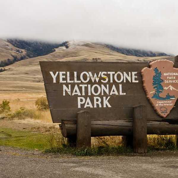The sign upon entering Yellowstone National Park with hills int he background
