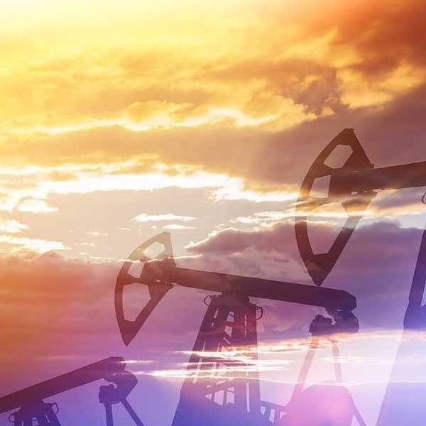 The silhouette of oil pump jacks against a setting sun
