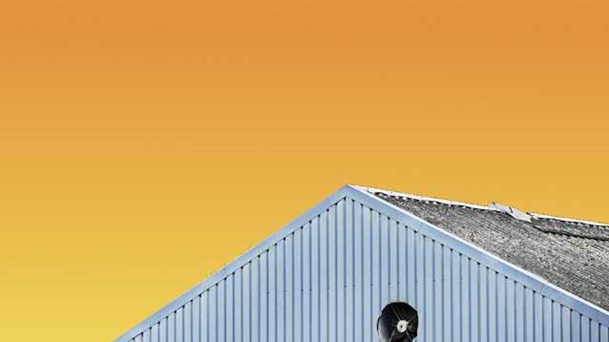 The top of a gray building with an orange sky in the background