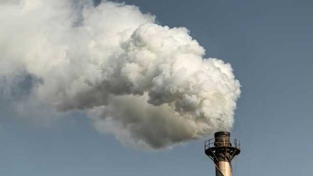 The top of a smokestack with smoke billowing from the top