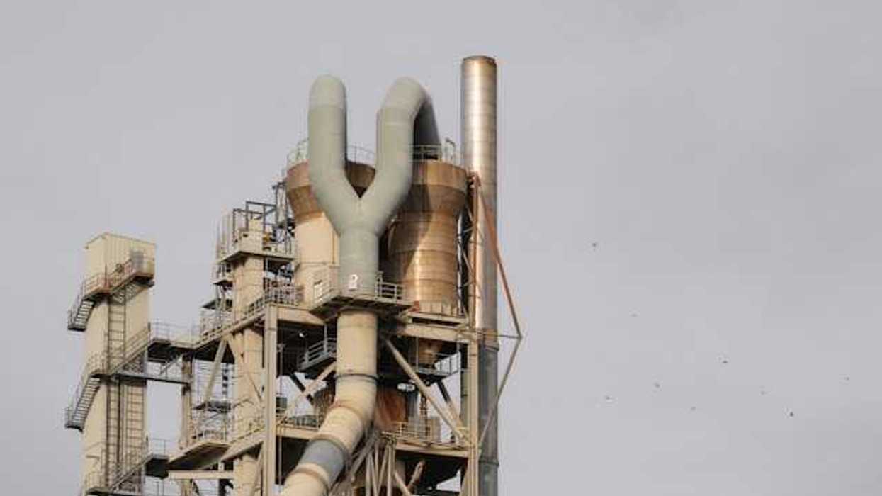 The top portion of an industrial factory with tubes, stairs, and smokestack