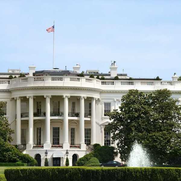 The White House during summer. Green grass, fountain, American flag flying.