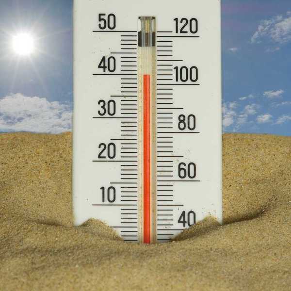 Thermometer stuck in the sand under a hot sun, reading 40 degrees C and 104 degrees F