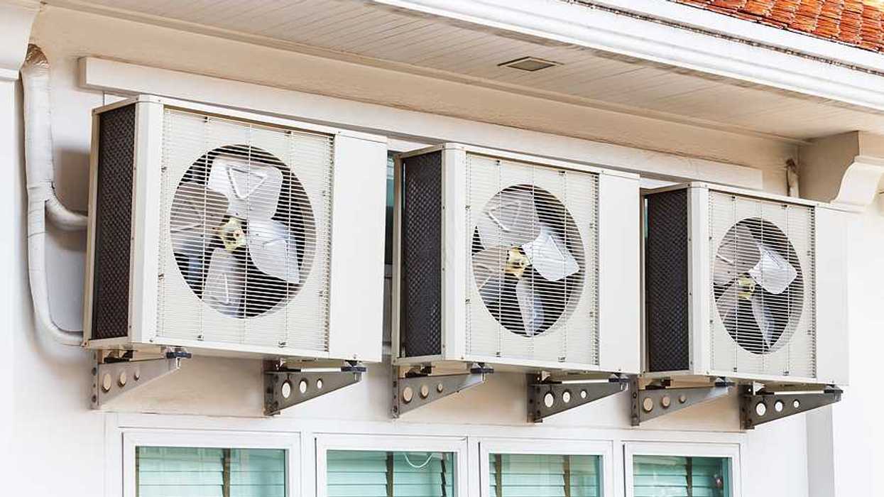 Three air conditioning units installed on a wall above windows