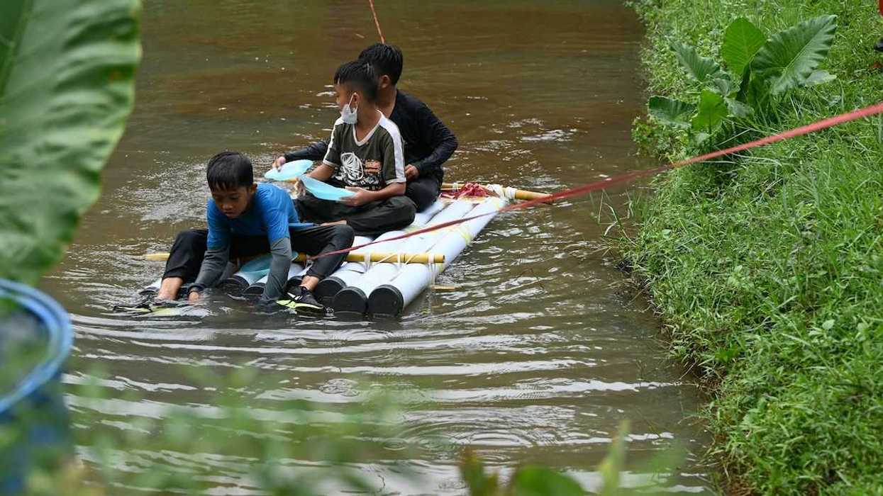 Three boys on a homemade raft being towed to shore in a water rescue
