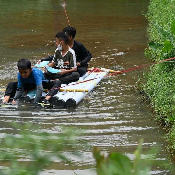 Three boys on a homemade raft being towed to shore in a water rescue
