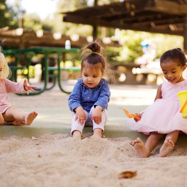 Three children sitting and playing in playground sand