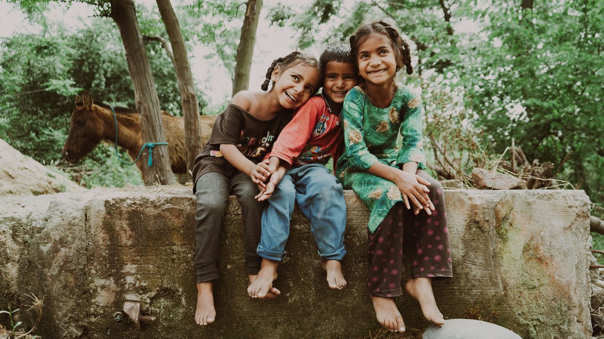 three children sitting on a rock