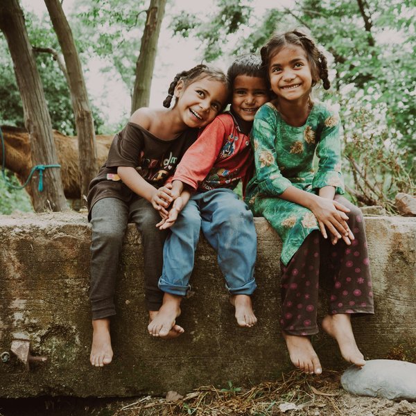 three children sitting on a rock
