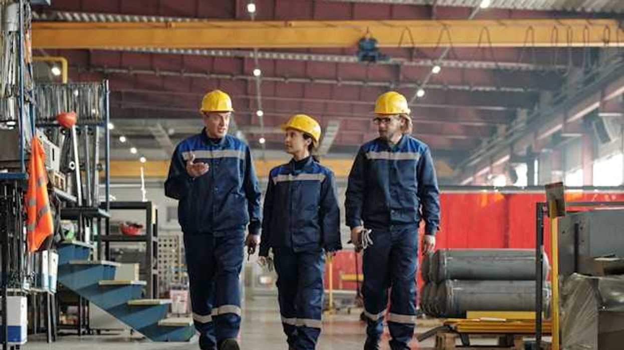 Three factory workers walking through a factory
