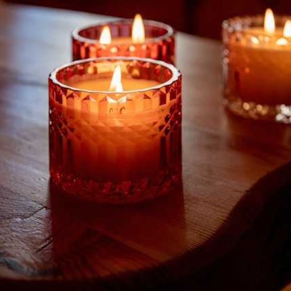 Three lit candles in amber colored glass containers