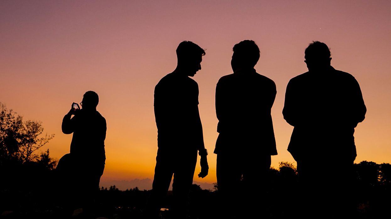 Three men silhouetted against a sunset