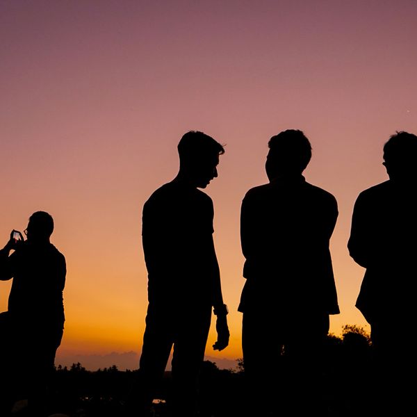 Three men silhouetted against a sunset