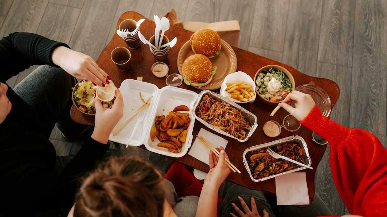 Three people seated and eating fast food from their takeout containers shot from above