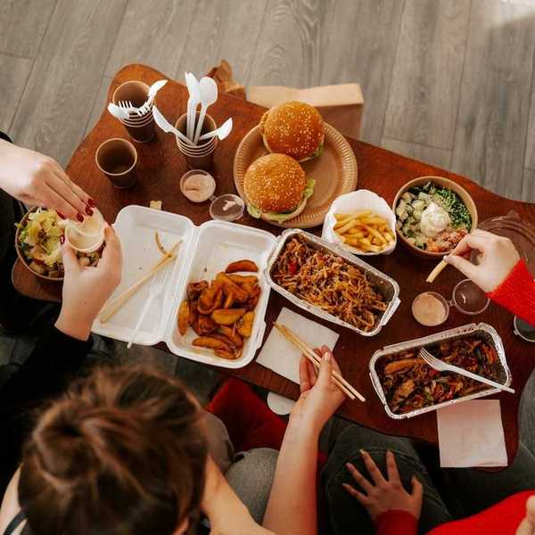 Three people seated and eating fast food from their takeout containers shot from above