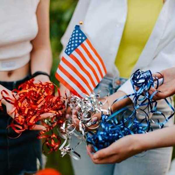 Three people standing in a circle holding a small American flag and red, silver and blue ribbons