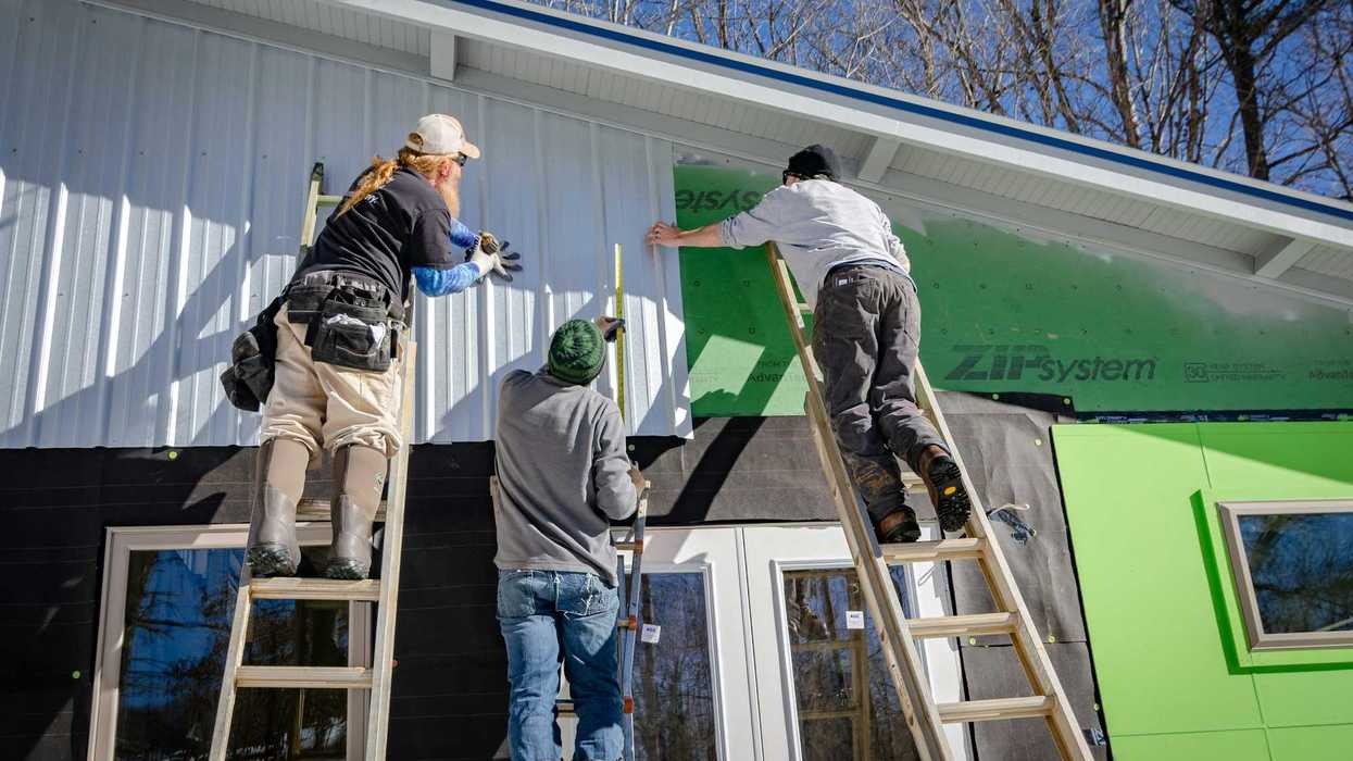 three person climbing on ladder doing home construction.
