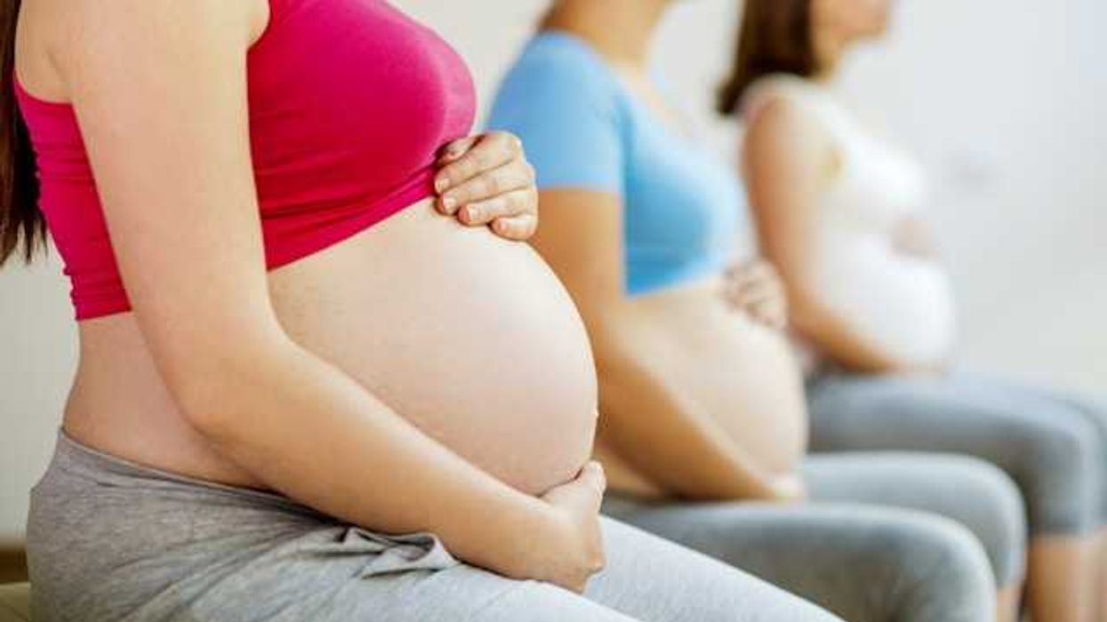 Three pregnant women in athletic clothing sitting in a row