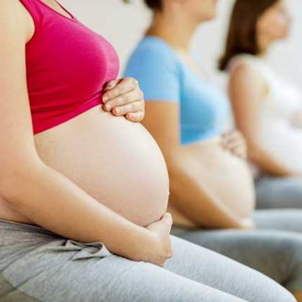 Three pregnant women in athletic clothing sitting in a row