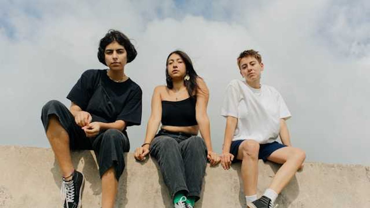 Three teens sitting on a concrete wall