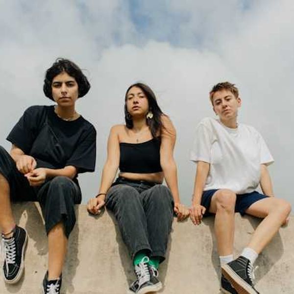 Three teens sitting on a concrete wall