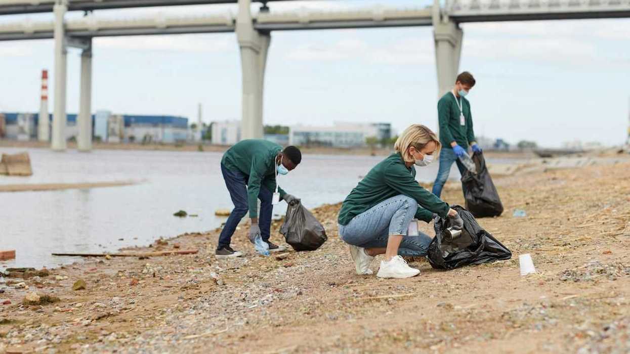 Three volunteers with garbage bags scour waterfront for trash