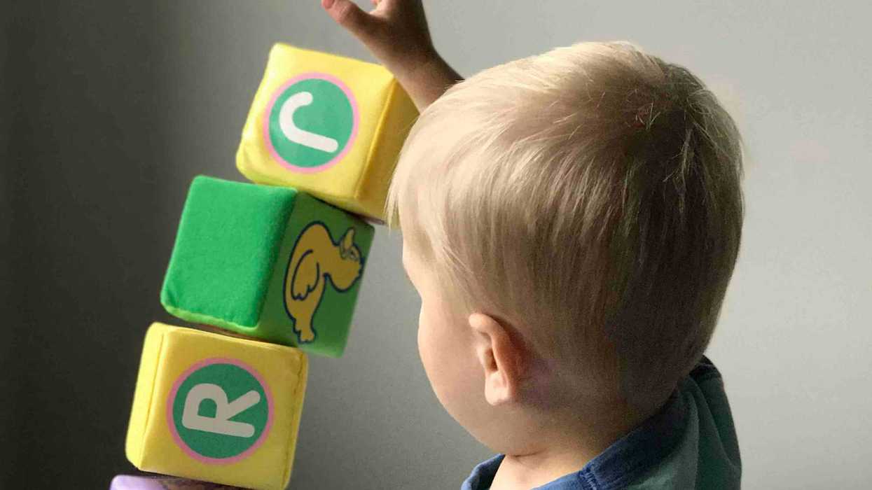 Toddler playing with blocks on white wooden table.