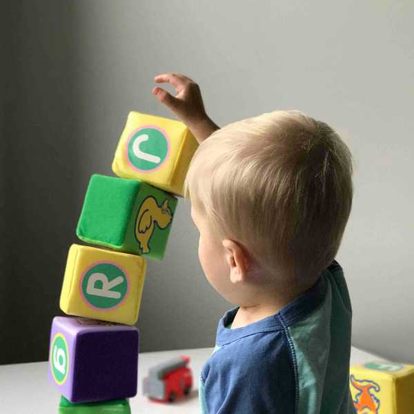 Toddler playing with blocks on white wooden table.
