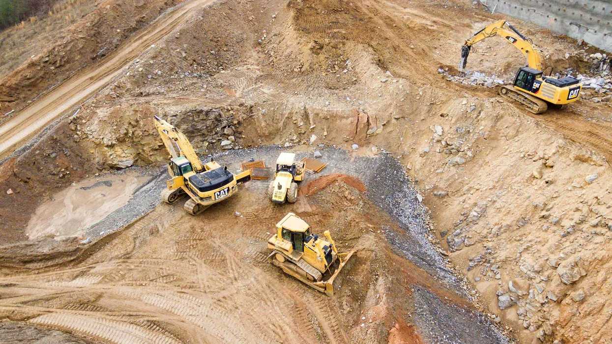 top view photography of four heavy equipment in mining quarry during daytime.
