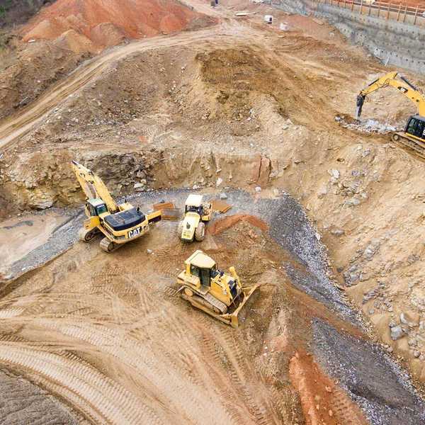 top view photography of four heavy equipment on quarry at daytime.