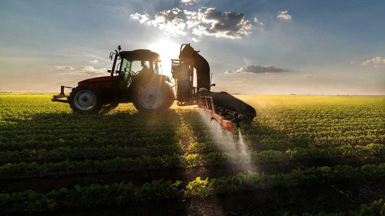 Tractor mounted machine spraying a crop with herbicides or fertilizer