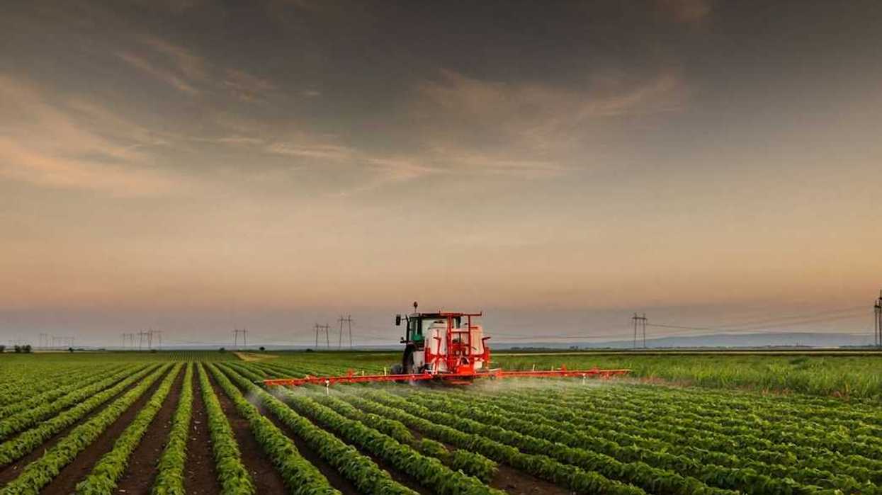 Tractor mounted with spraying equipment treating a crop of soybeans