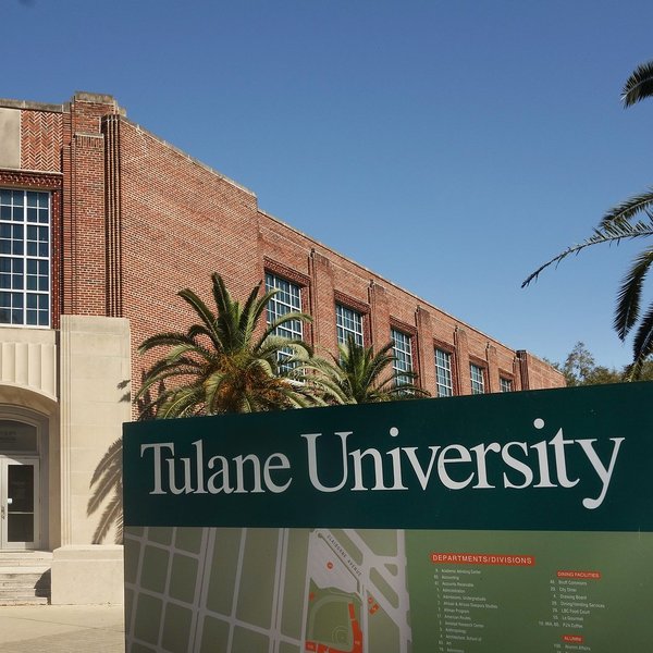 Tulane University sign with red brick academic building and palm trees in background.