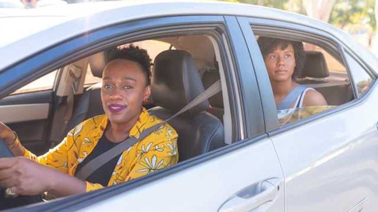 Two African woman in a car, a driver and a back-seat passenger on a sunny day