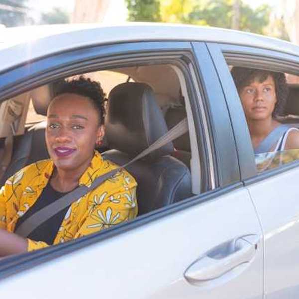 Two African woman in a car, a driver and a back-seat passenger on a sunny day