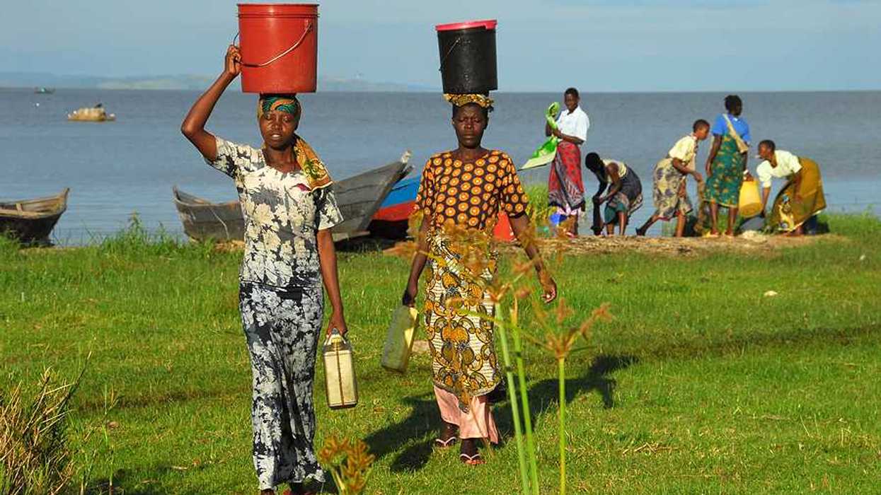 Two African women walking away from Lake Victoria with buckets on their heads