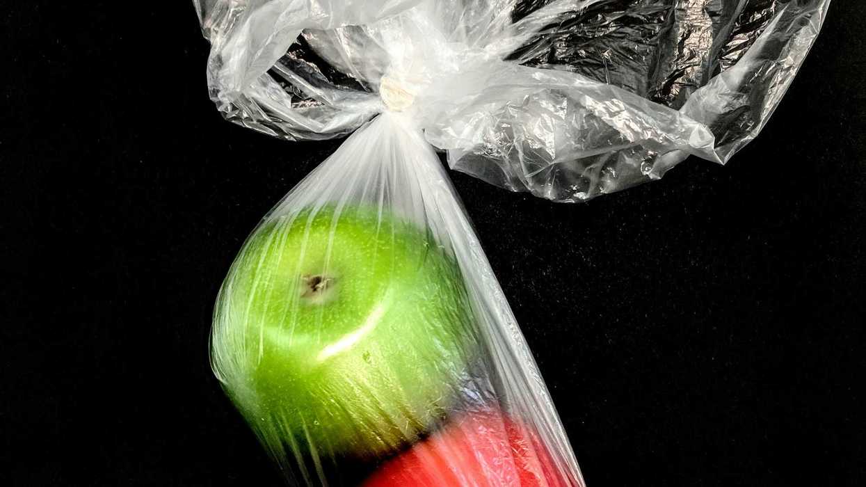 Two apples, red and green, in a clear plastic bag.